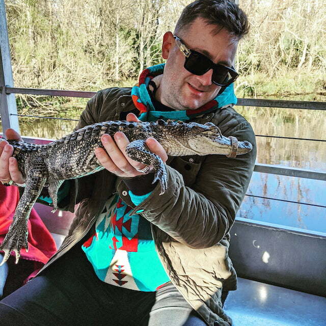 clint holding an alligator on a boat in a swamp near new orleans